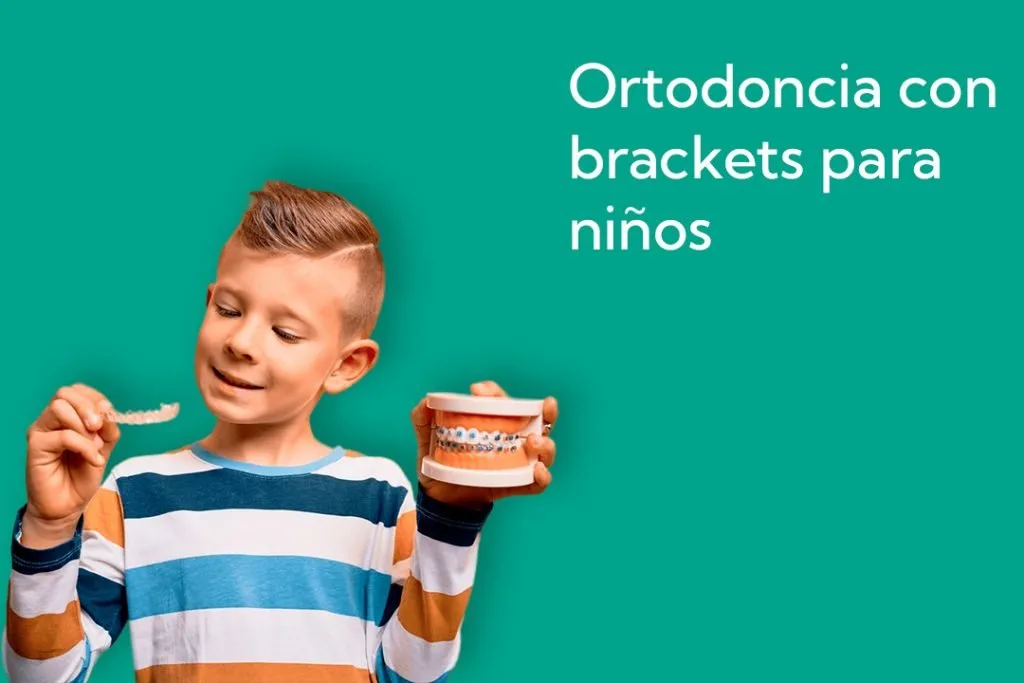 Niño mostrando un modelo dental con brackets, representando tratamientos de ortodoncia fija para niños en la clínica dental Avilés DDC Fuengirola.