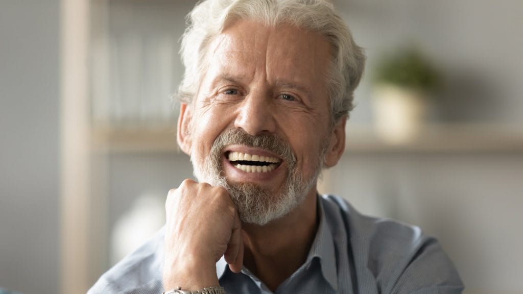 Hombre sonriente mayor mostrando una sonrisa saludable, representando los exitosos resultados de la técnica revolucionaria de rehabilitación dental Same Day ofrecida por Avilés Digital Dental Clinic en Fuengirola.