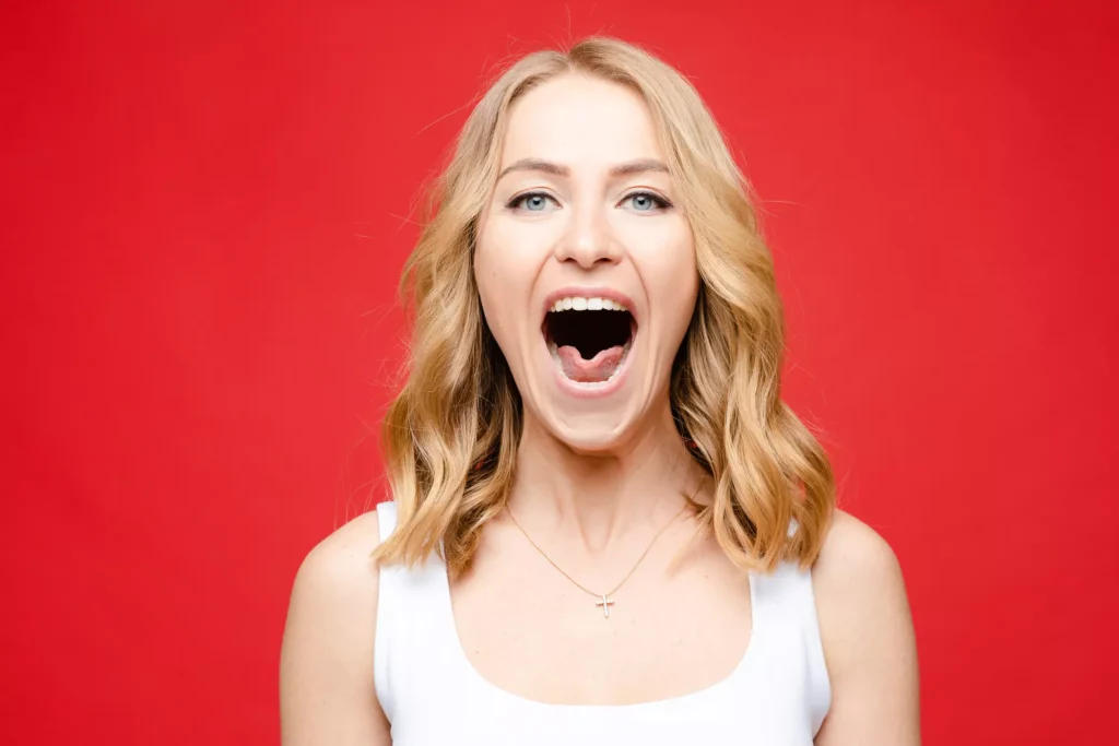 Mujer rubia con la boca abierta, evidenciando boqueras en la comisura de los labios.