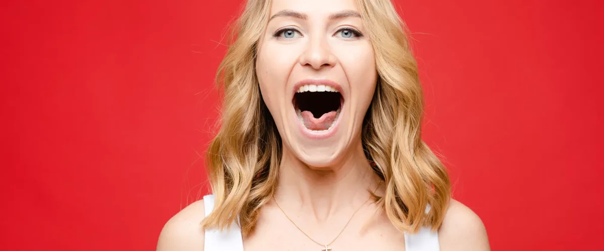 boqueras Blonde woman with her mouth open, showing angular cheilitis at the corner of her lips.